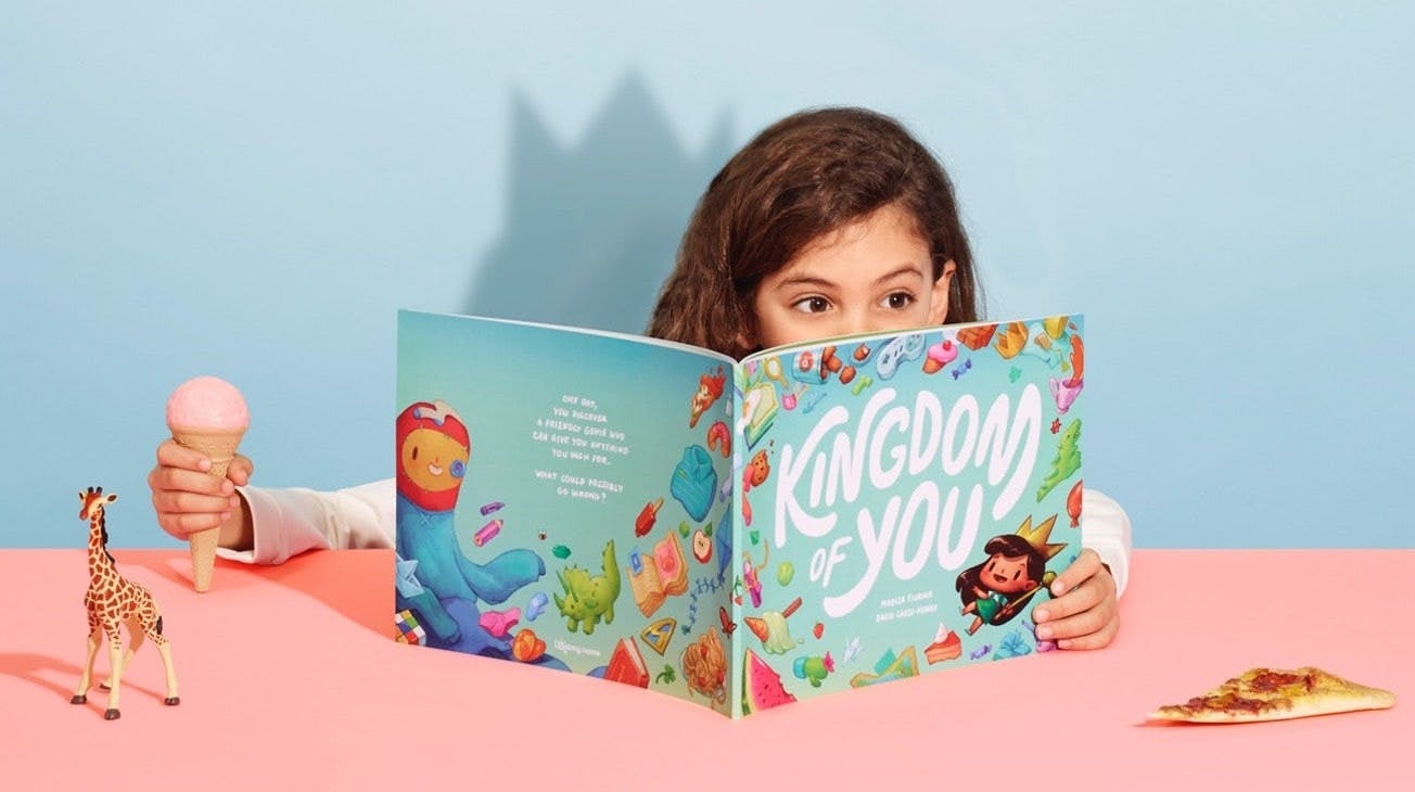 A little girl holding an ice cream as she reads the Kingdom of You book