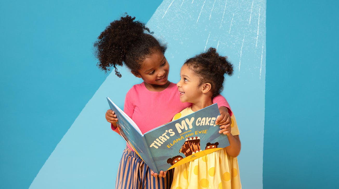 Two sisters hugging and reading the book