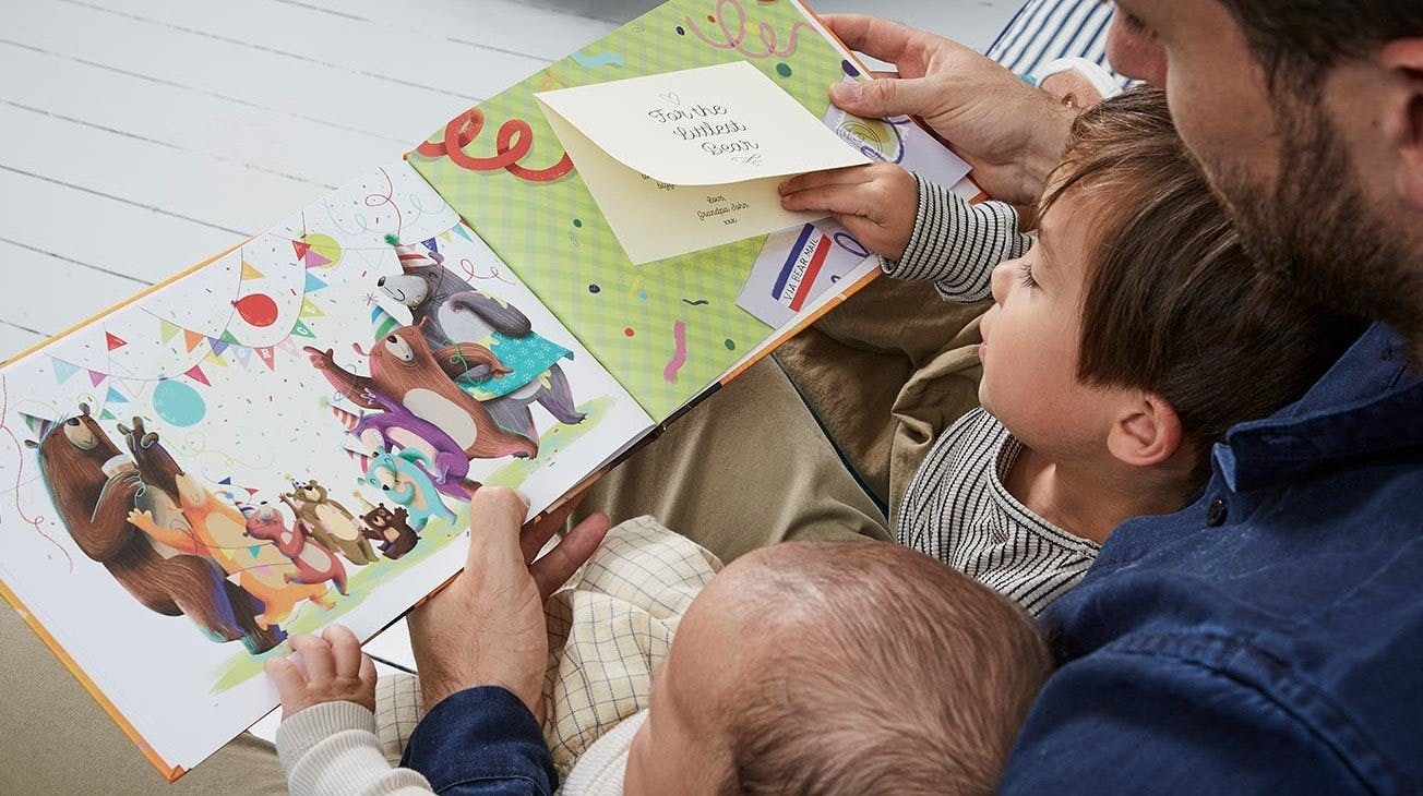 An image of the father with his two sons reading the Littlest Bear book to them