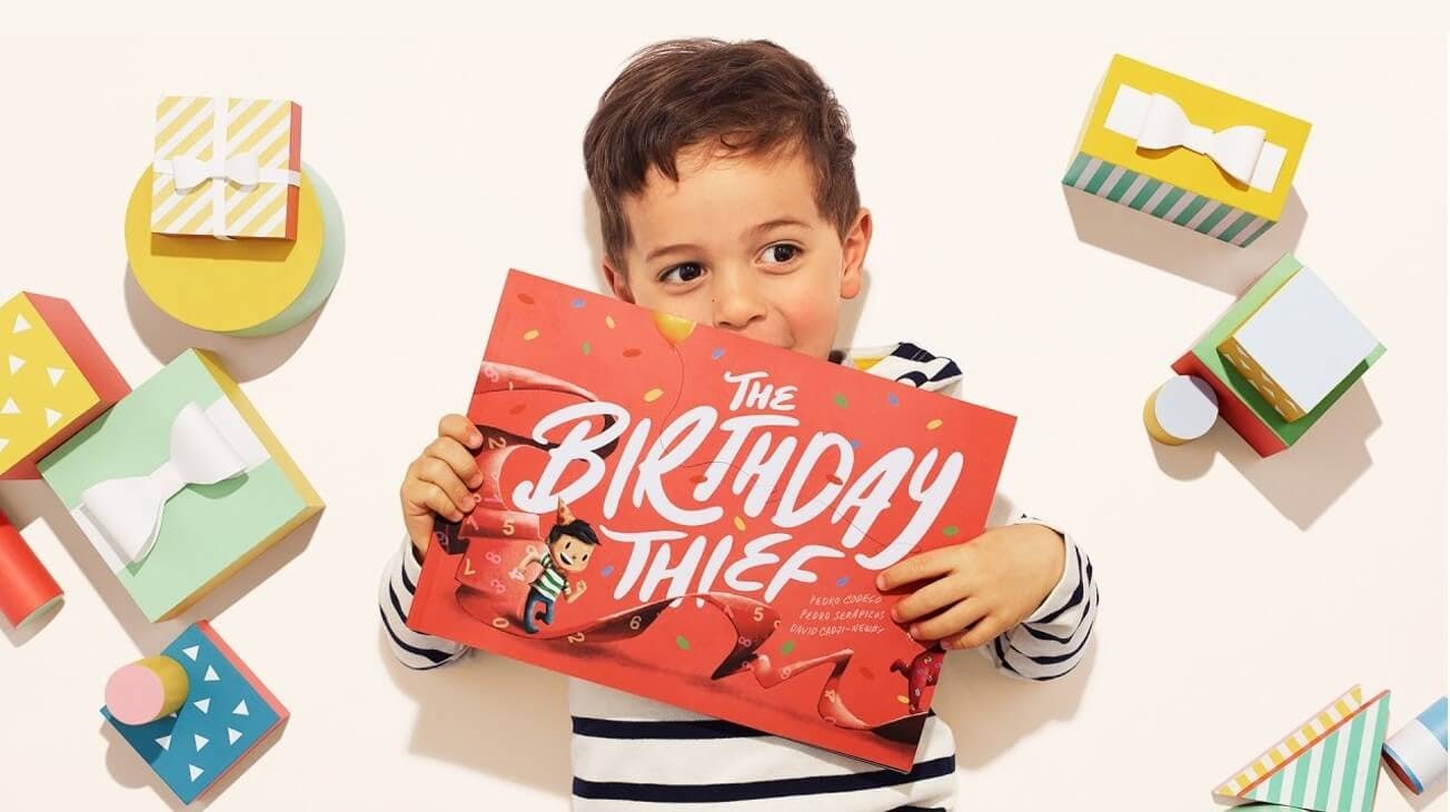 A little boy holding his birthday thief book